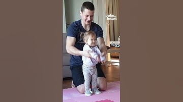 Toddler Girl Does Stretching Exercises at Home With Dad