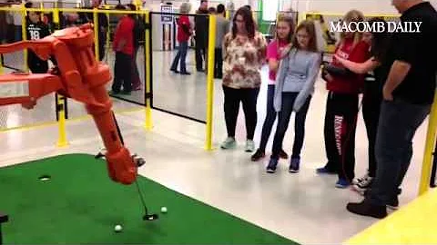 Romeo students work on their putting skills while touring R&E Automated in Macomb.