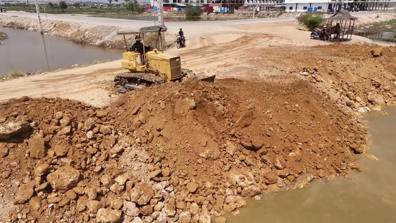 Very good. Land cleaning expert. Using dozer KOMAT'SU Pushing Stone Soi With Dump Trucks