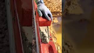 laying red bricks with cement mortar for wall construction and building infrastructure development