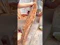 chopping a large rough tree log bark using a sharp hand axe tool outdoor in carpentry workshop