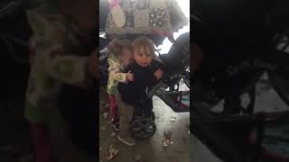 Little girl bites boy on back near stroller