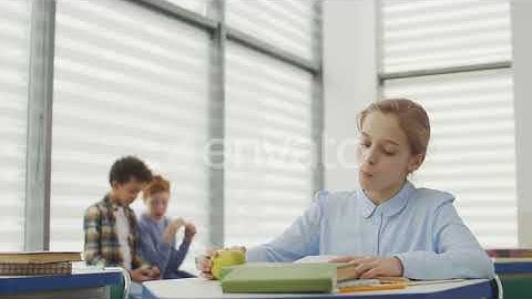 School Girl Eating Apple and Reading in Classroom | Stock Footage - Envato elements
