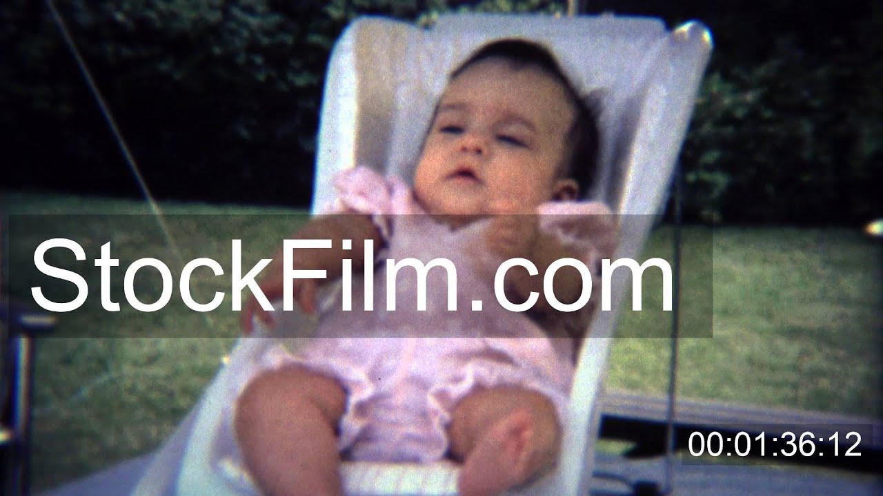 1971 Baby flailing legs and arms around in small white chair. BOULDER
