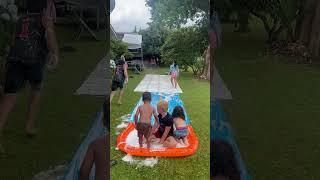 Little boy gets tripped by his friend riding on Slip 'N Slide