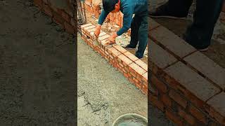 Laying red bricks with cement neatly to build a building wall at an outdoor construction area