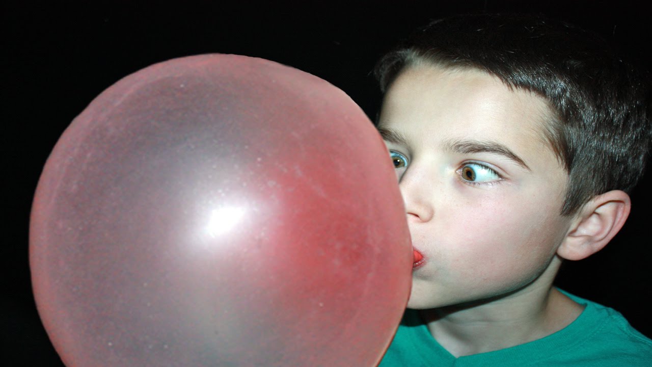 Мальчик с большим шаром. Пузырь из жвачки. Надувает пузырь из жвачки. Самый большой шар из жвачки. Самый большой надутый пузырь из жвачки.