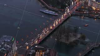 Aerial view of traffic on a Mont Blanc bridge with Swiss flags fluttering in Geneva at night, with
