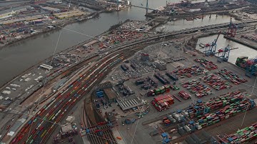 Aerial view of large cargo container terminal in Hamburg with reveal of the river and city