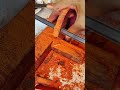 scraping red sandalwood block with sharp metal scraper tool to produce fine aromatic wood powder