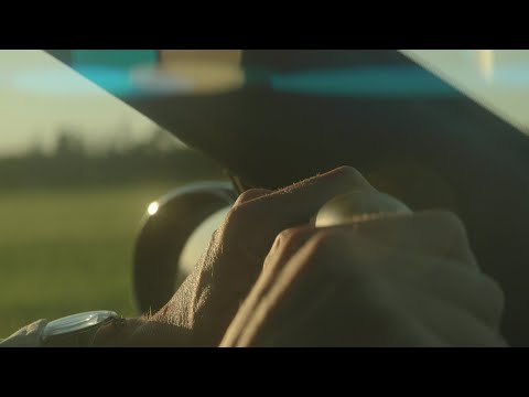 Hands grabbing steering wheel of sports car in sunset, anamorphic flares