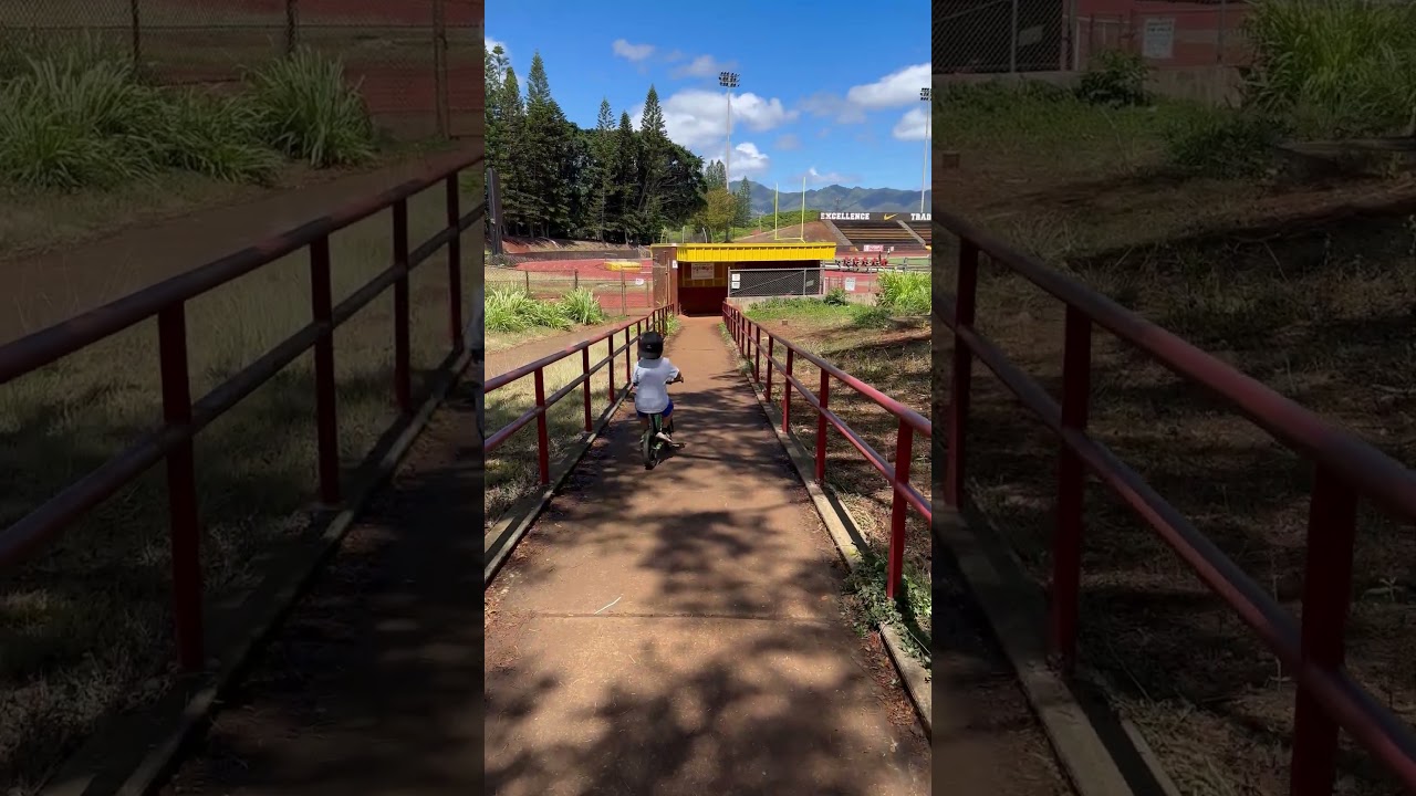 Boy in backwards baseball hat rides bike downhill between handrail and crashes into wall bumps head