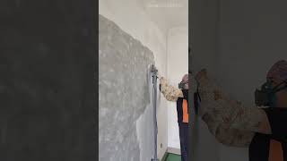Sanding the concrete wall to smooth the surface using an electric wall sander machine with vacuum