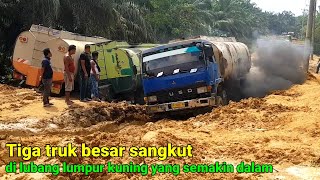 Tiga truk besar sangkut di lubang lumpur kuning yang semakin dalam