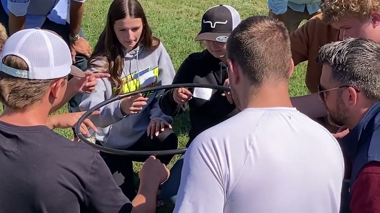 Video preview image of A large group of students engage in outdoor teambuilding exercises.; click to visit the ParentSquare post with the video