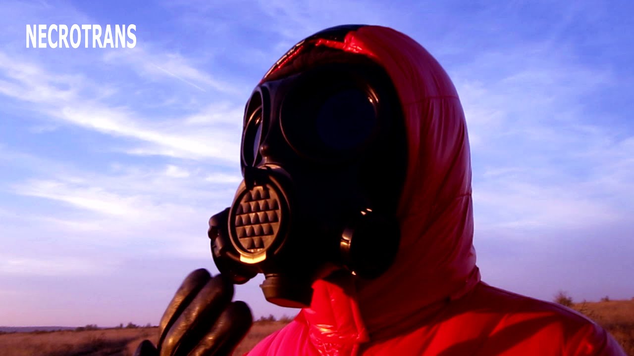 Walking in a winter red glossy jacket with a hood and prints, a leather suit and a black respirator.