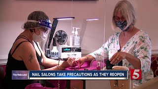 A nail salon that has reopened is using plexiglass and face shields to
protect customers workers from covid-19.