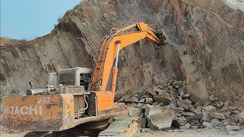 Powerful Excavator in Action: Breaking Rocks with Hydraulic Hammer and Chisel