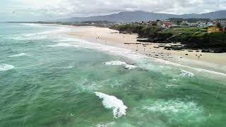 Experience The Breathtaking Beauty Of A Coastal View With Waves And Beachgoers At The Seaside