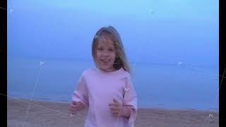 Girl running across sandy beach toward camera at dusk