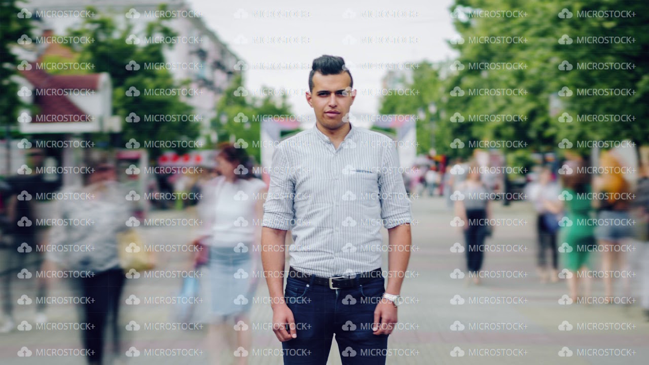 Time lapse of good-looking young Arab with serious face standing alone in street