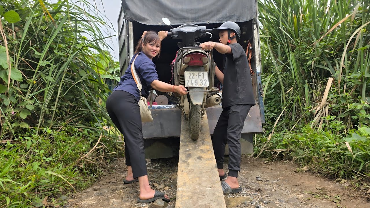 Girl repairs and restores broken motorbike in the middle of the road.