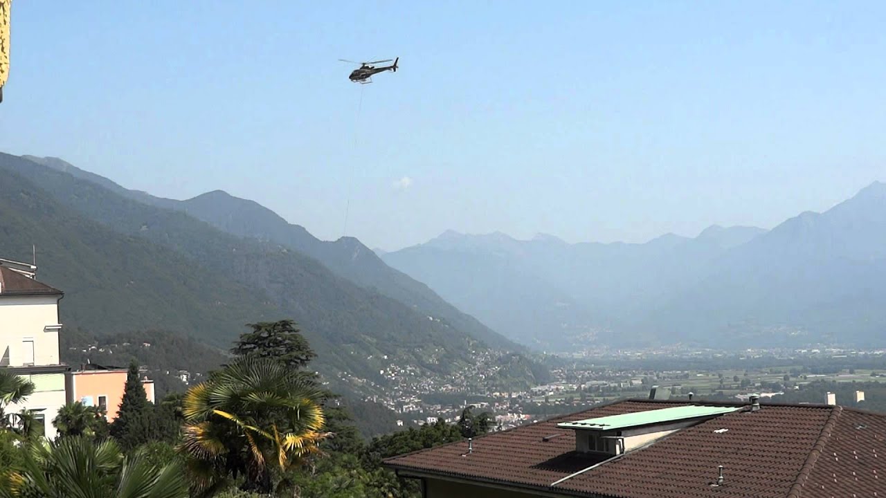 gewerblicher Baustellen-Helikopter rotiert über dem alten Dorfkern von Orselina