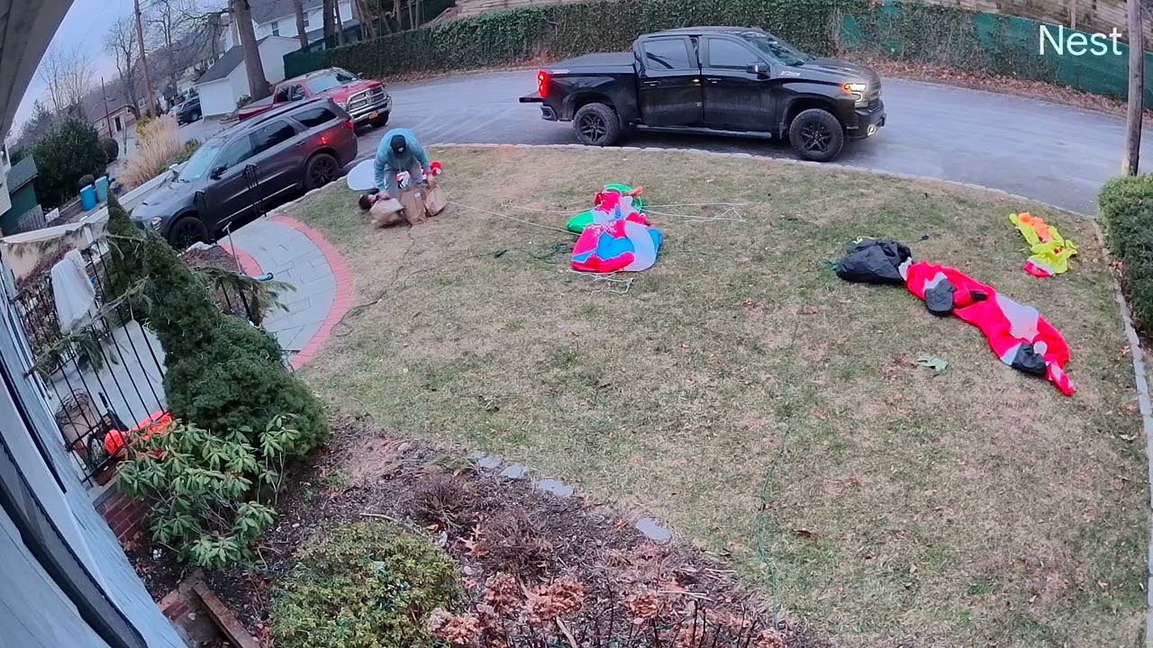Boy holding grocery bags trips over Christmas decorations on front lawn (Security camera)