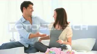 Pregnant Couple Sitting On Bed