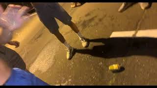 Guys shotgun beers then one attempts to kick the can then trips and falls back on street
