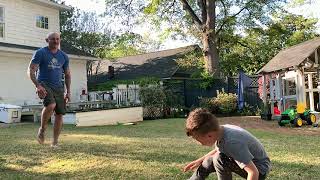 Dad kicks red bouncy ball that hits boy on a sensitive area