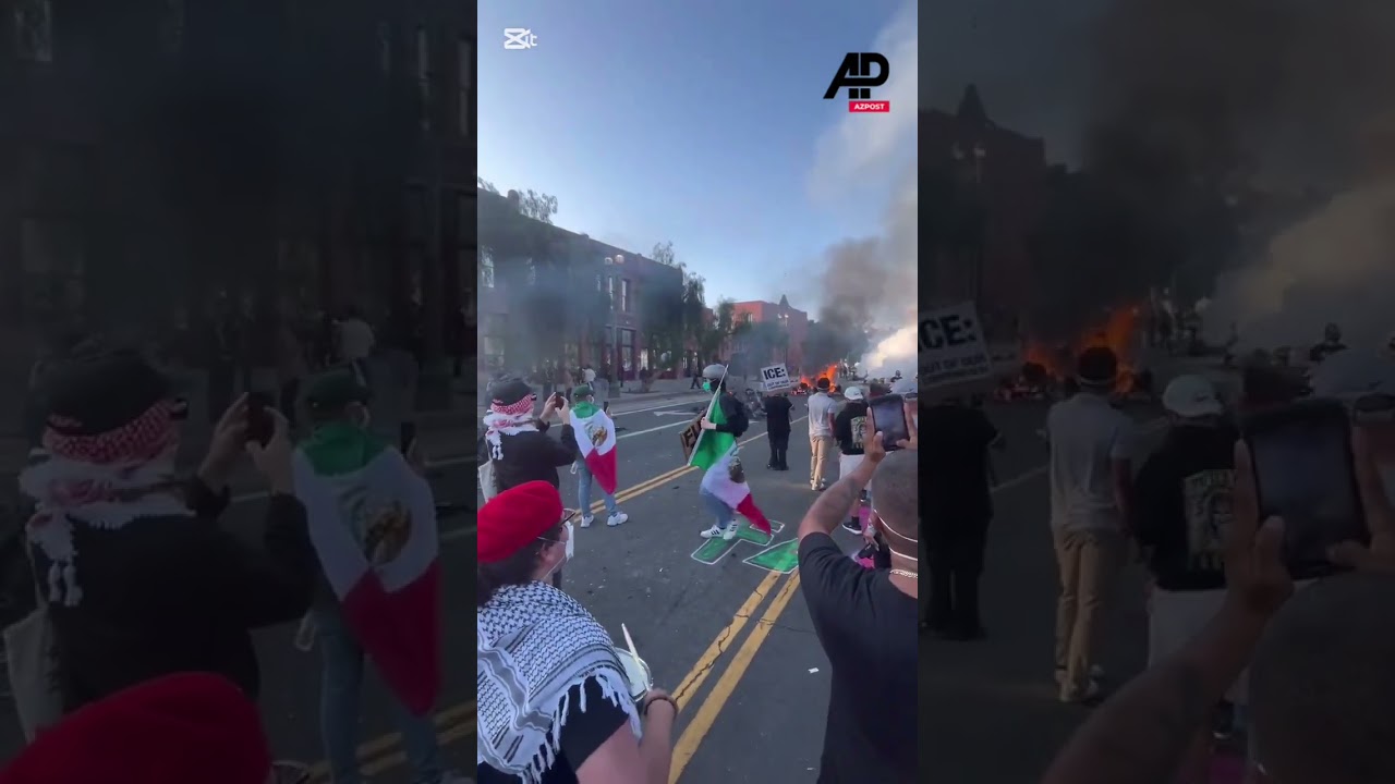 Protester drums as smoke rises from burned down vehicles in LA protests 