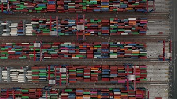 Overhead top down aerial view of automated cranes moving colorful cargo containers in Hamburg port