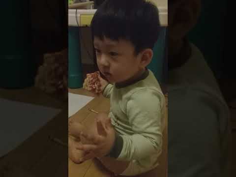 20 months old baby is eating pizza by himself
