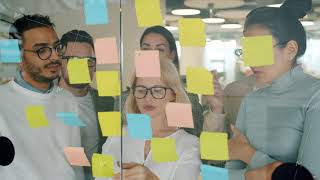 Creative team of coworkers using sticky notes for problem solving planning work in office Wealth
