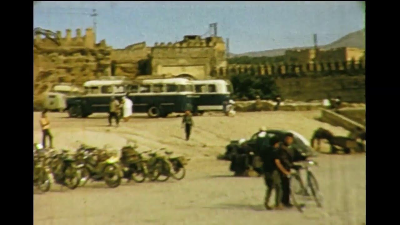Still from colour home-movie footage, 1965: buses and mopeds outside the walls of Tangier, filmed by a passenger arriving on the Mons Calpe from Gibraltar.