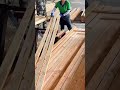 The process of smoothing long wooden planks using an industrial planing machine in an open workshop