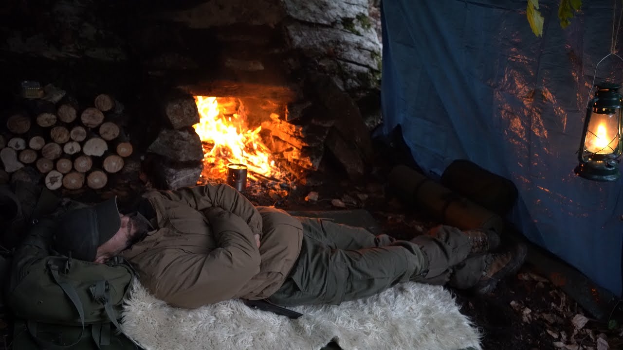 Sleeping in the wild. Shelter building with Big Stone fireplace with chimney. Warm survival shelter