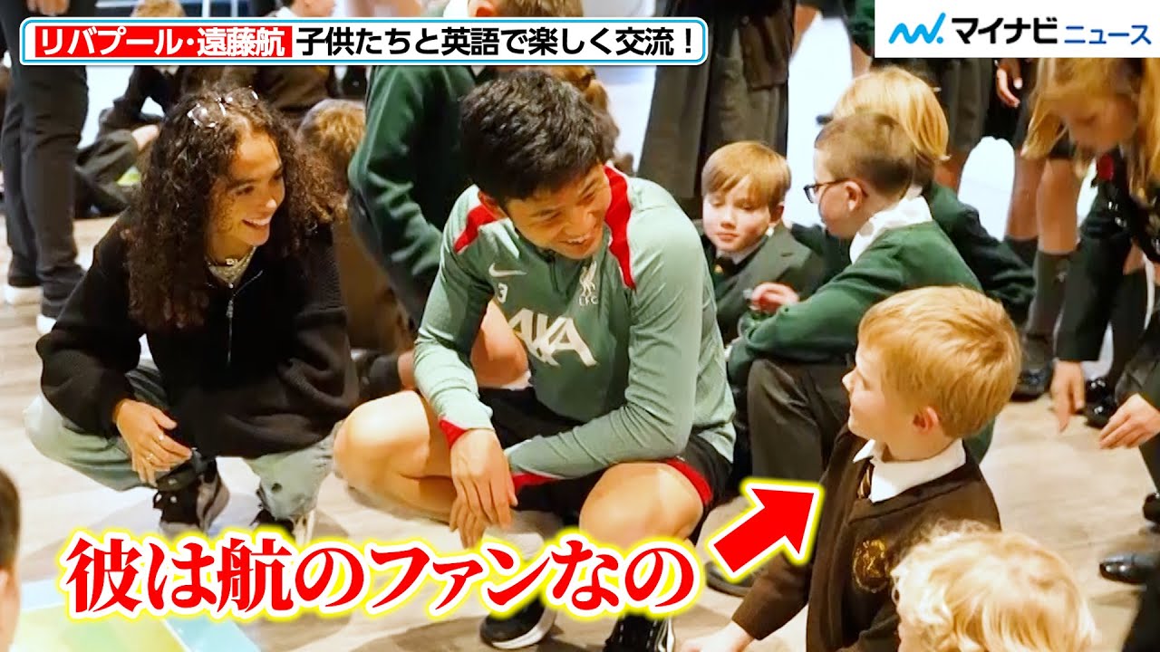 Liverpool's Wataru Endo smiles as he converses with a boy who is a