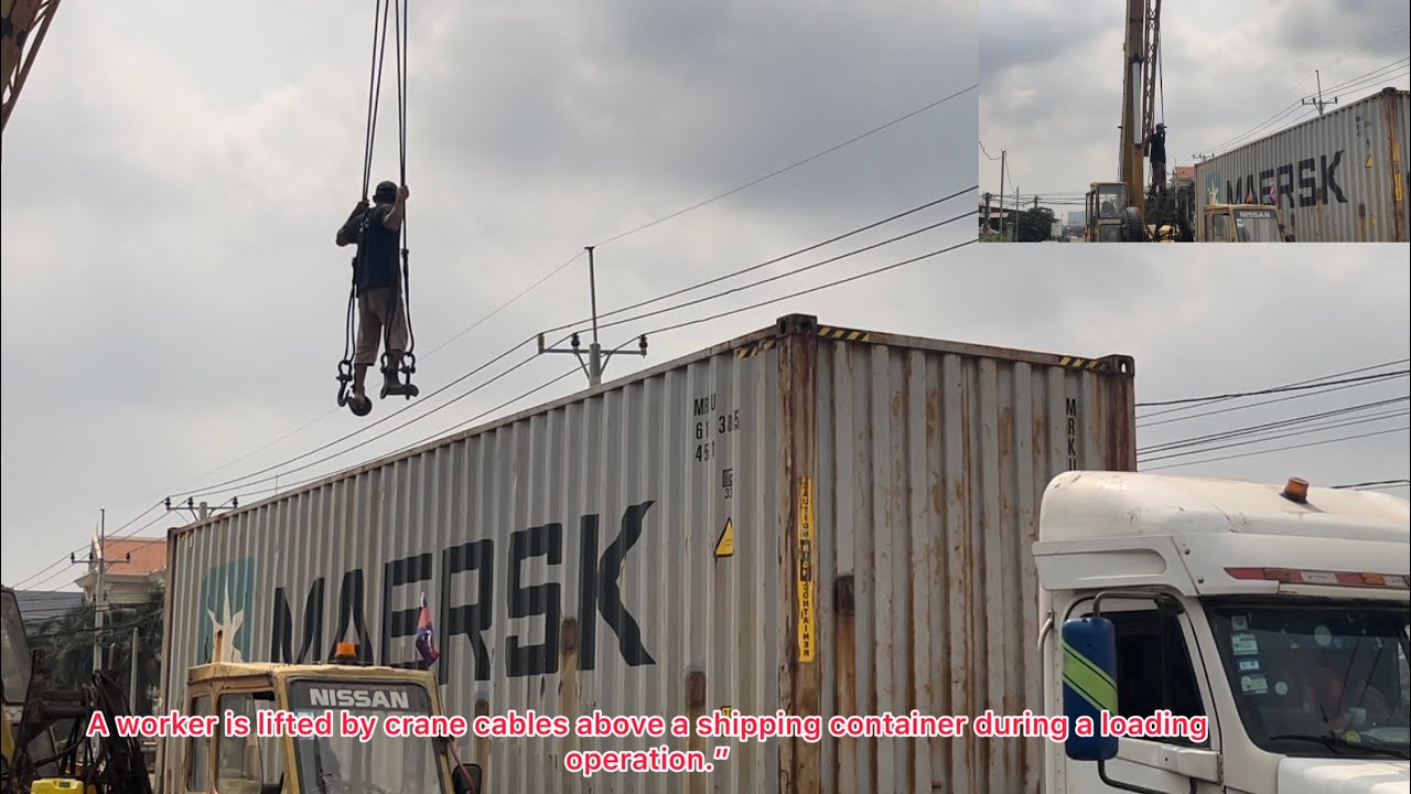 A worker is lifted by crane cables above a shipping container during a loading operation.”