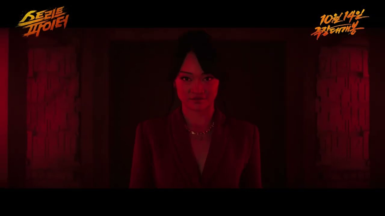 붉은 조명의 어두운 방 한가운데 선 붉은 옷차림 여성