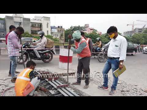 Workers repair a bridge expansion joint on Mahatma Gandhi Flyover in Delhi, 2021