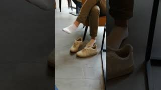 Shoeplay And Shoeless In Sneakers In Crowded Café