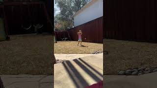 Girl in purple Nike shirt dances around on grass in backyard then kicks soccer ball at her own face