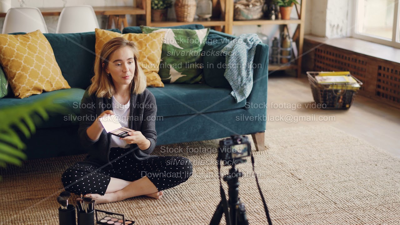 Beautiful young lady vlogger is recording video about new make-up products and tools using camera on