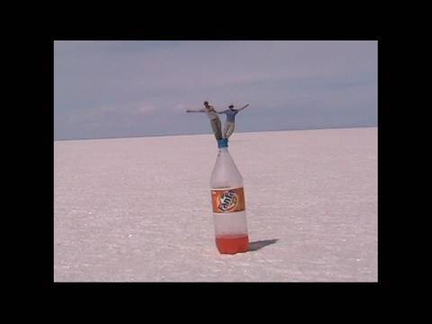 Standing on a Bottle, a Bizarre Perspective;  Salt Flats of Uyuni, Bolivia