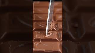 Ultra-realistic ASMR video of a giant milk chocolate bar being sliced with a sharp knife.