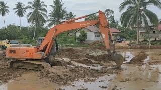 EXCAVATOR HITACHI MANEUVERING IN THE RICEFIELD.