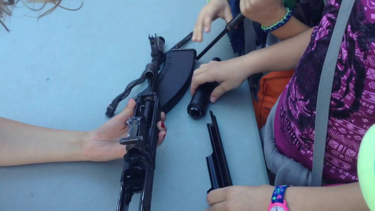 A girl learn Russian children how to deal with AK47