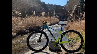 川の流れる林道をマウンテンバイクで走る動画